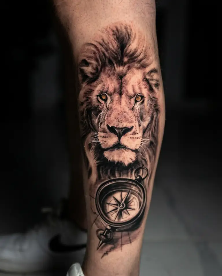 Black and grey realism lion and compass tattoo on the calf.