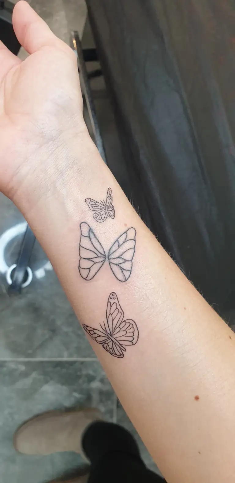 Bilekte küçük minimal fine line kelebek dövmesi.